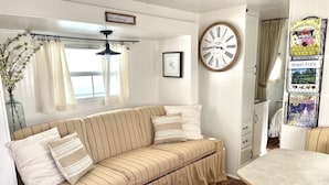 A cozy living room with a striped sofa, a wall clock, and a decorative sign.