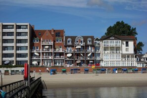 A beachfront hotel with multiple balconies, a pier, and beachside seating. - Nordland Appartments - Apartment Sylt - Directly by the sea, you can't get any closer! - (Wyk auf Föhr)
