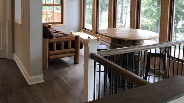 Een houten interieur met een eettafel, banken en grote ramen.