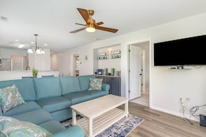 A living room with a teal sofa, a wooden coffee table, and a ceiling fan.