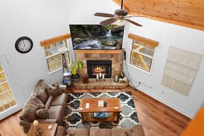 A cozy living room with a fireplace, a television mounted above it, and a comfortable seating area. - Oktoberfest + Walk to Downtown Helen + Hot Tub (Helen)
