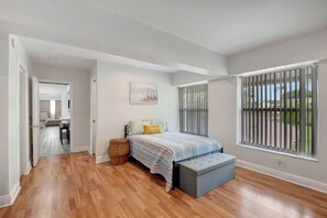 A bedroom with a bed, a bench, a painting, and a window with blinds. - Private Boca Paradise Heated Pool Quiet Area (Boca Raton)