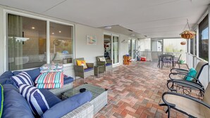 A covered patio area with a sofa, chairs, and a dining table.