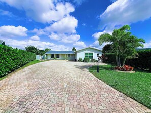 A house with a paved driveway leading to a front door, surrounded by well-maintained hedges and a lawn. - Private Boca Paradise Heated Pool Quiet Area (Boca Raton)