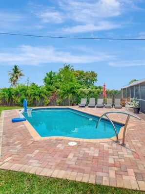 A rectangular swimming pool with a brick border, surrounded by a grassy area and trees. - Private Boca Paradise Heated Pool Quiet Area (Boca Raton)