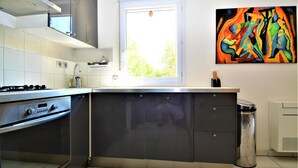 A modern kitchen with a gas stove, a built-in oven, and a large island with dark cabinets. - 2 bedroom gorgeous apartment in Orange (Orange)