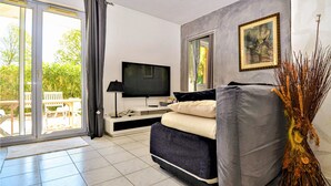 A modern living room with a sofa, a TV, and a dining area visible through a glass door. - 2 bedroom gorgeous apartment in Orange (Orange)