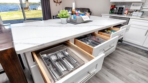 Eine moderne Küche mit Marmorarbeitsplatte, zwei Schubladen mit Besteck und Blick ins Freie.