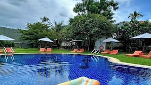 Una piscina con agua azul cristalina, rodeada de sillas de descanso y sombrillas.