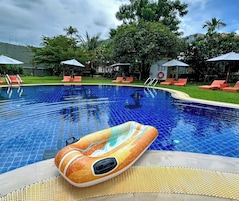 Una piscina con agua azul cristalina, rodeada de sillas de descanso y sombrillas.