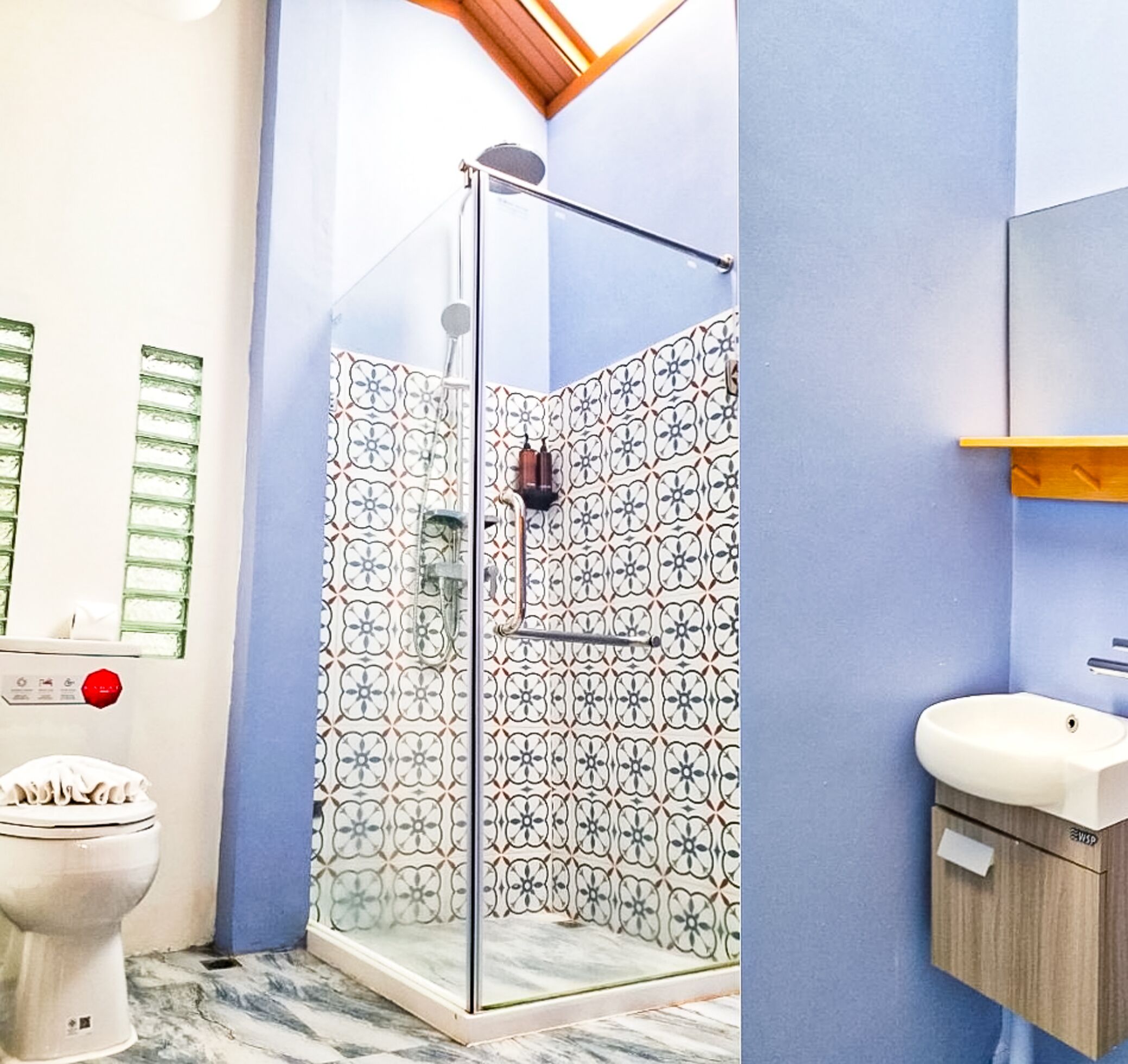 A bathroom with a glass shower enclosure, a toilet, and a sink.