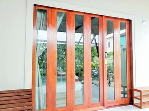 A sliding glass door with a wooden frame, leading to an outdoor area with a bench and a table. - Kata Forte Resort (Karon)