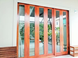 Una puerta corrediza de vidrio con marco de madera, que da a un espacio exterior con un banco y una mesa.