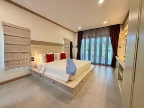 A modern bedroom with a large bed, built-in storage drawers, a bedside table, and a view of the outdoors through large windows.