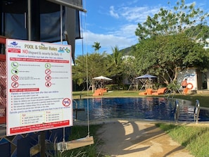 Una piscina al aire libre, sillones reclinables de piscina