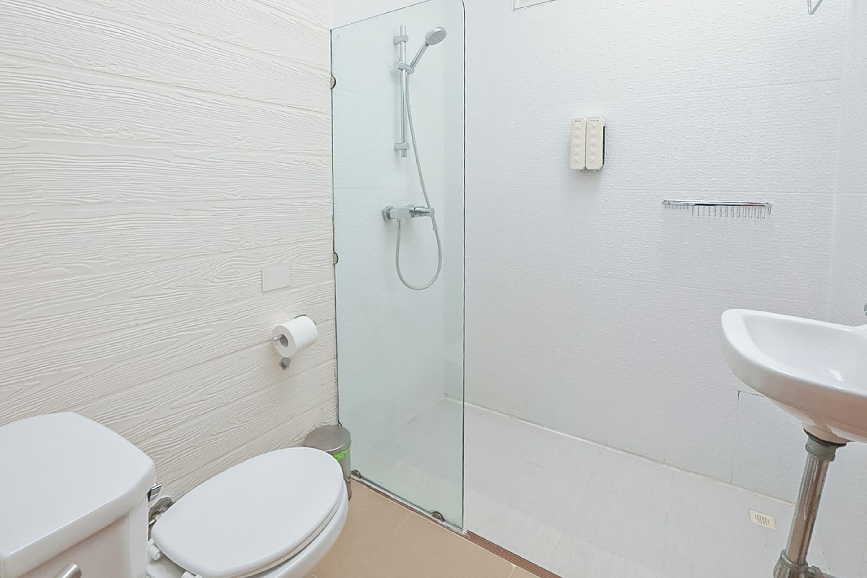 Un baño moderno con inodoro, cabina de ducha de vidrio y lavamanos.