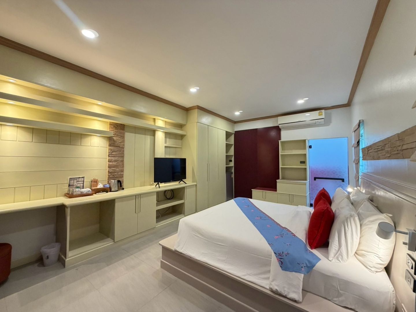 A modern hotel room with a large bed, a TV, and built-in storage cabinets.