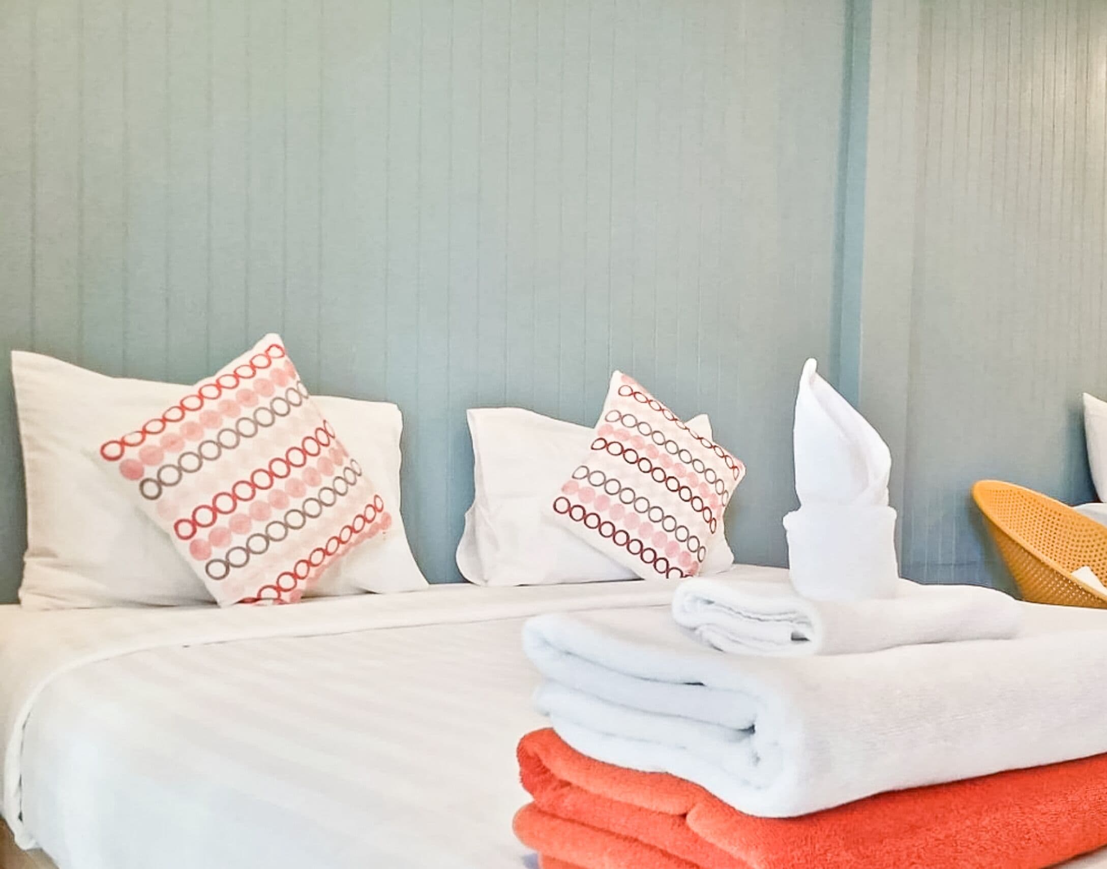 Ett hotellrum med en säng, kuddar och hopvikta handdukar.