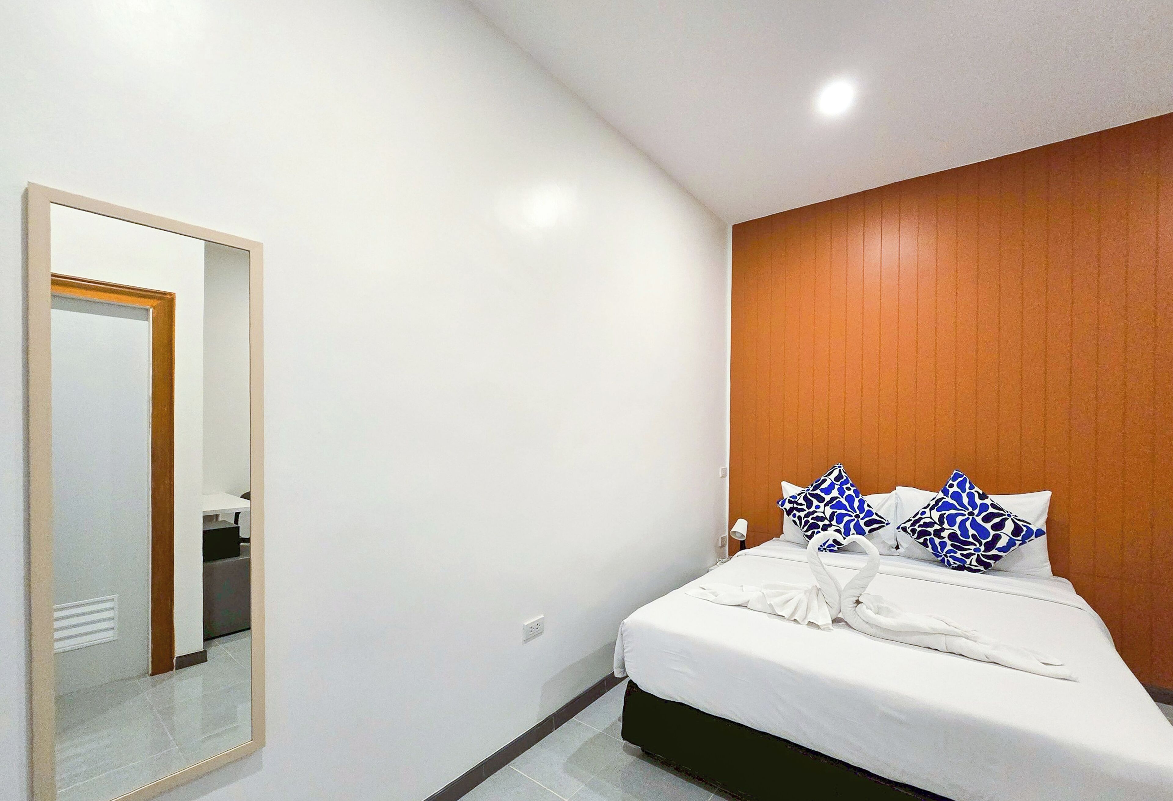 A hotel room with a bed, a mirror, and a wooden panel wall.