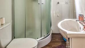 Ein Badezimmer mit Glasdusche, Toilette und Waschbecken mit Spiegel.