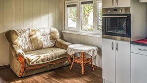 Ein gemütliches Zimmer mit einer gepolsterten Couch, einem kleinen runden Tisch und einer Küchenzeile mit Schränken und einem Backofen.