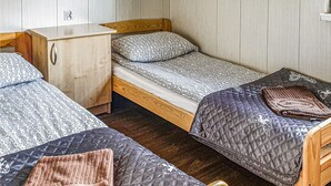 Ein kleines, kompaktes Zimmer mit zwei Einzelbetten, einem Nachttisch aus Holz und einem kleinen Holzschrank.