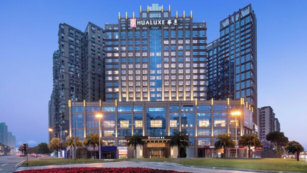 A modern hotel with a prominent Hualuxe sign, multiple floors, and a well-lit entrance. - HUALUXE Leshan by IHG (Leshan)