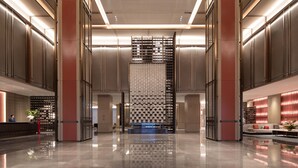 A spacious lobby with a central staircase, a reception desk, and a seating area with a sofa and coffee table. - HUALUXE Leshan by IHG (Leshan)