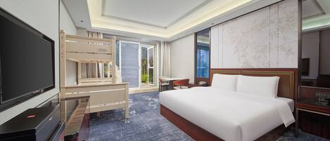 Una habitación de hotel con una cama grande, televisión, escritorio y balcón con vista a la ciudad.