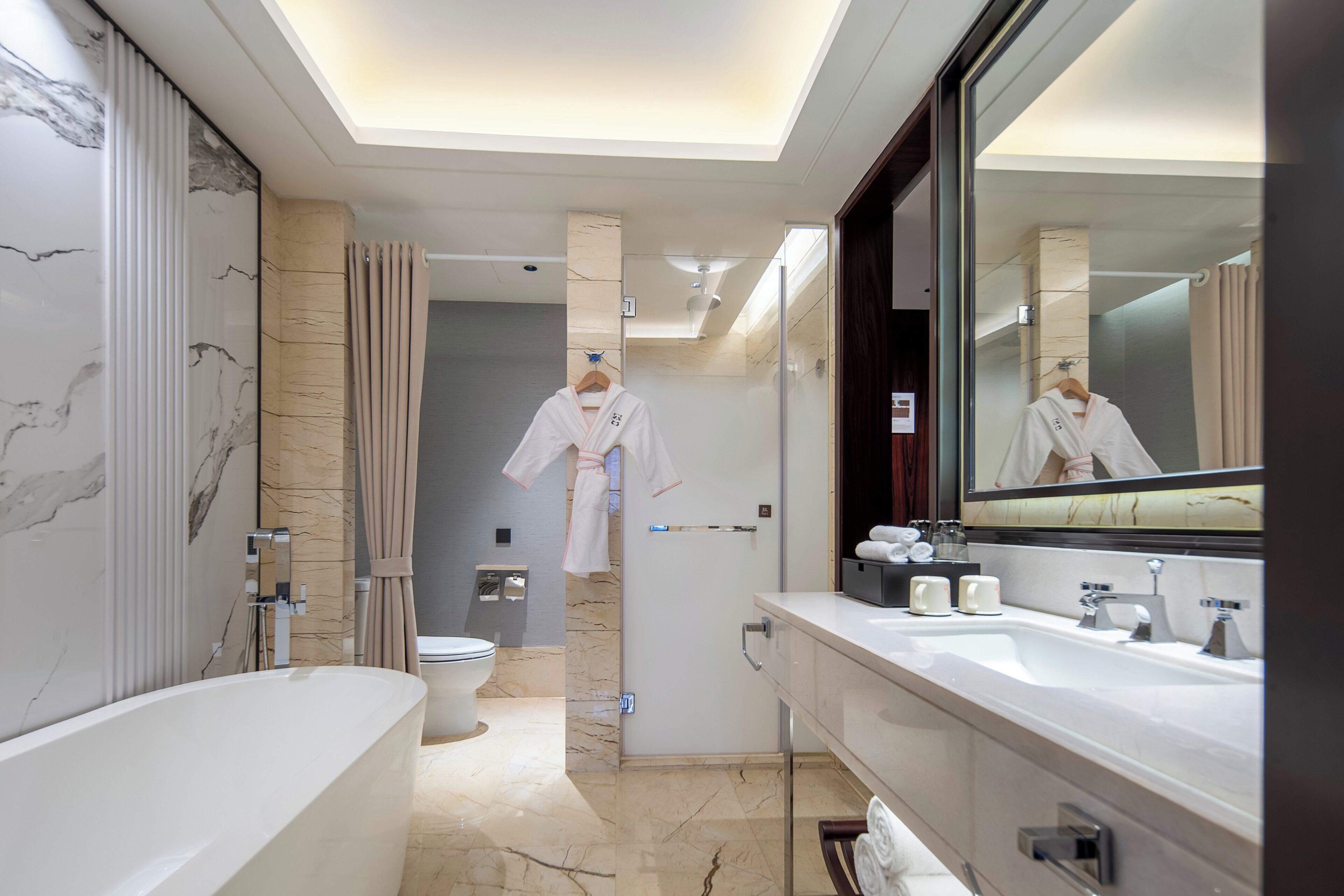 A modern bathroom with a bathtub, a large mirror, and a toilet.