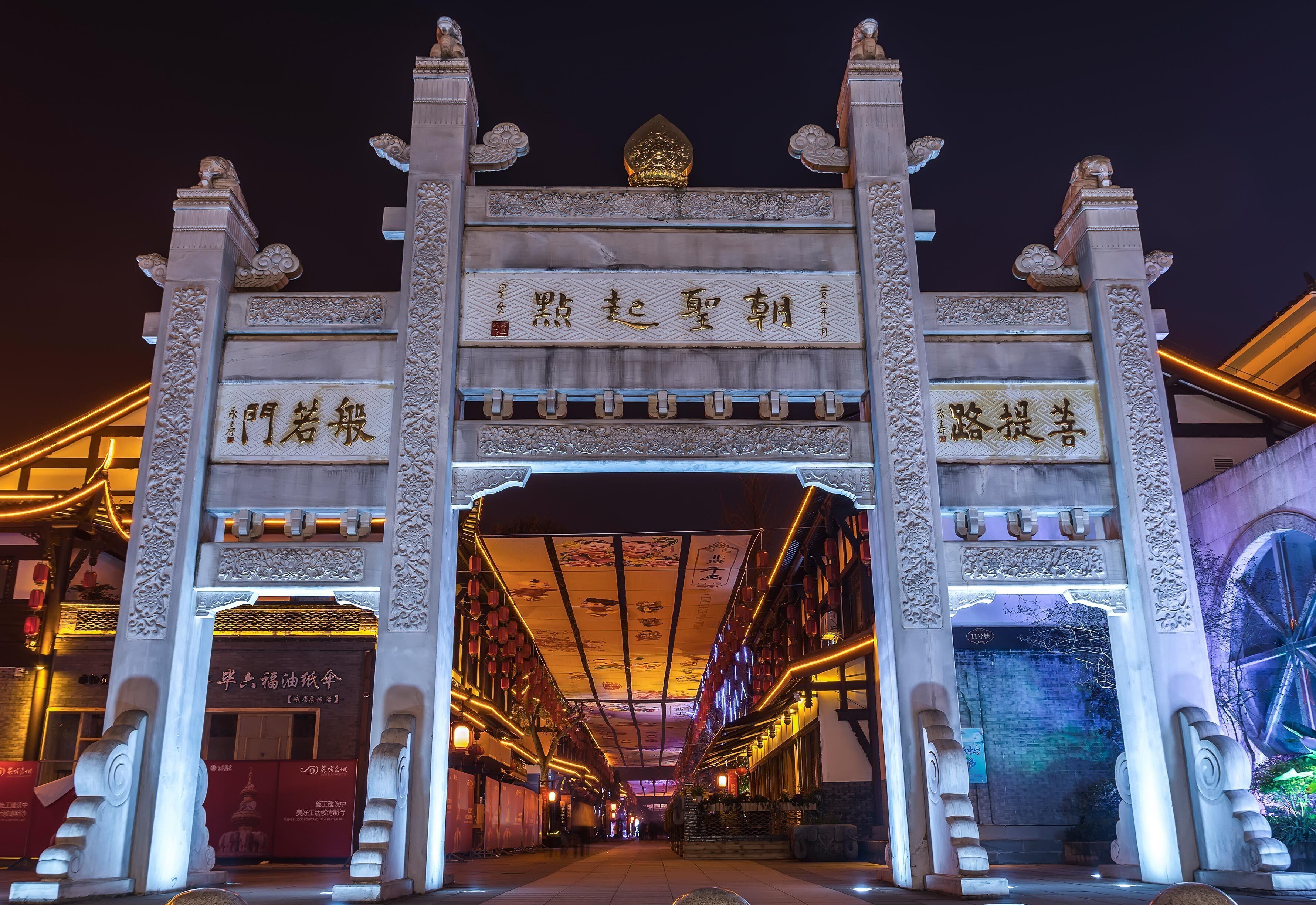 A traditional Chinese gate with intricate carvings and illuminated signs.