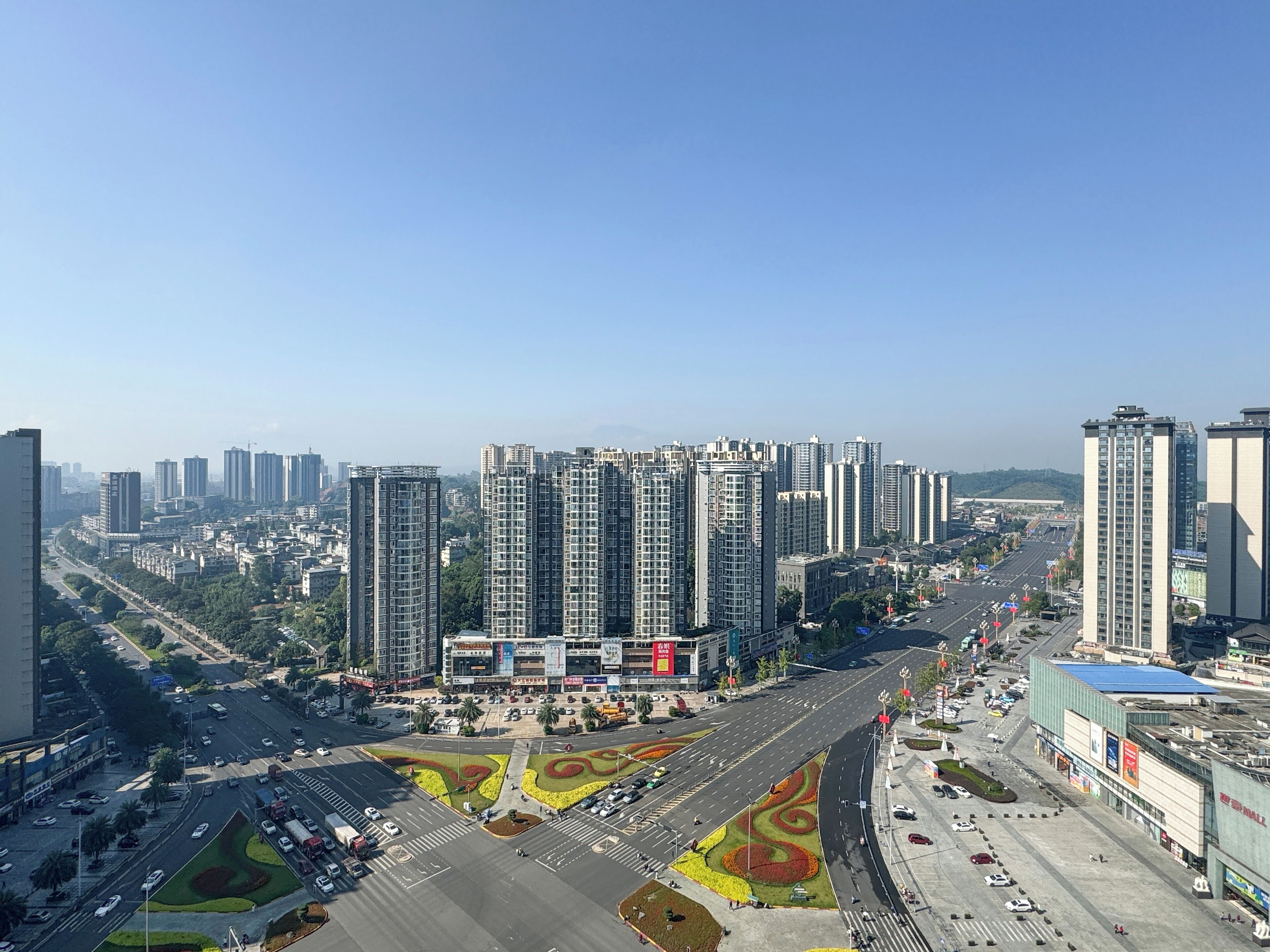 Un paisaje urbano con edificios altos, una avenida amplia y un gran edificio comercial.