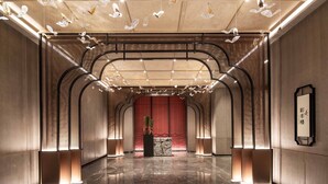 A spacious lobby with a polished marble floor, a reception desk, and a traditional red backdrop. - HUALUXE Leshan by IHG (Leshan)