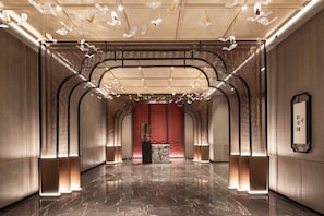 Experience the sleek, minimalist lobby with a polished floor, elegant columns, and a unique ceiling installation.
