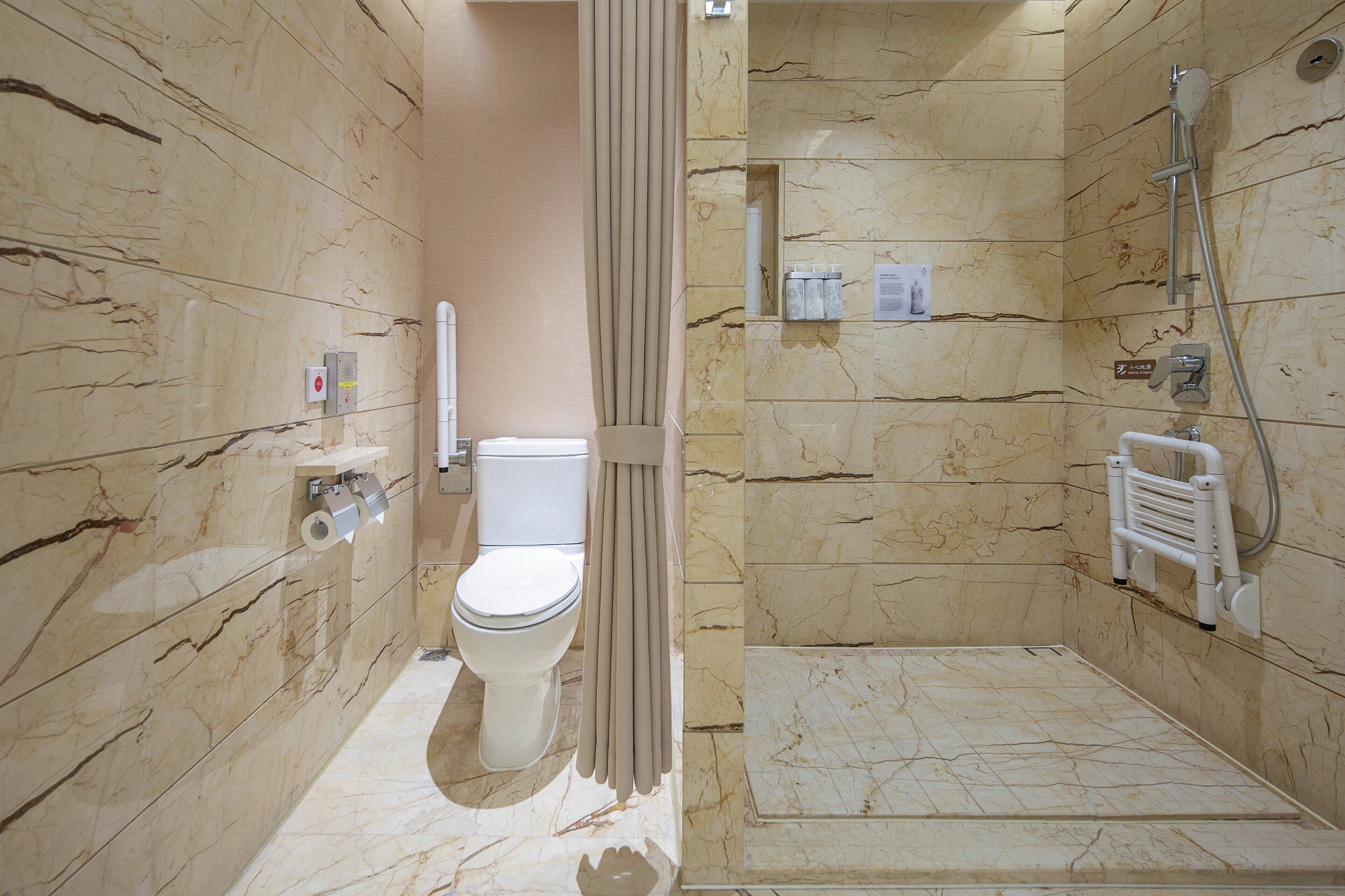 A bathroom with a toilet, shower, and marble walls.