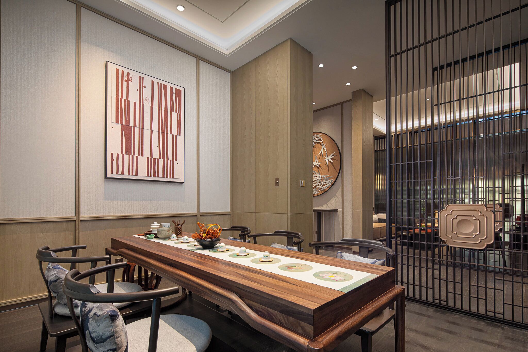A conference room with a long wooden table, chairs, a clock, and a decorative wall piece.