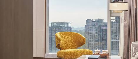 Un salón moderno con un sillón amarillo, una mesa de centro blanca y vistas a rascacielos.