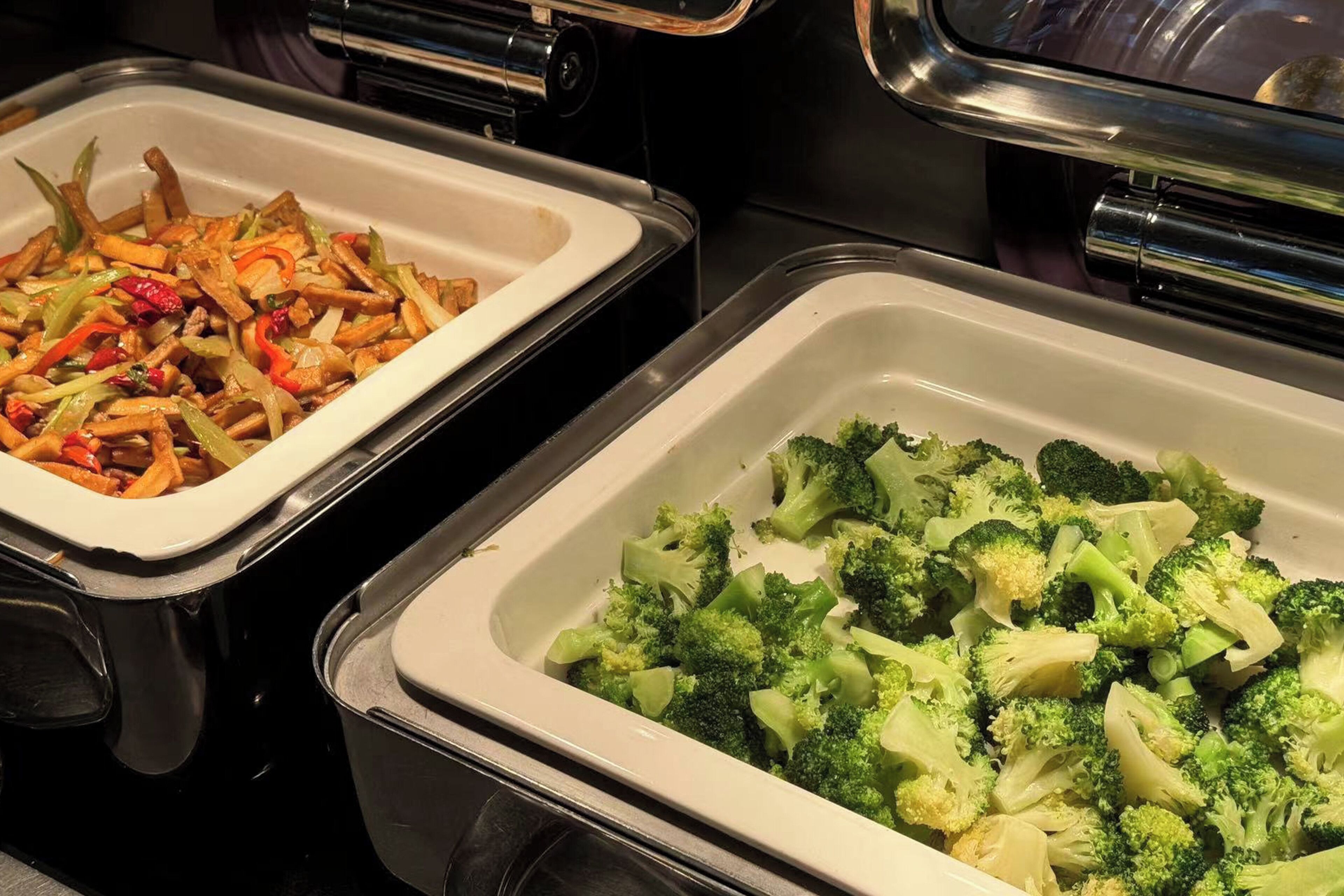 Deux plateaux de service, l’un contenant des légumes sautés et l’autre des brocolis cuits à la vapeur.