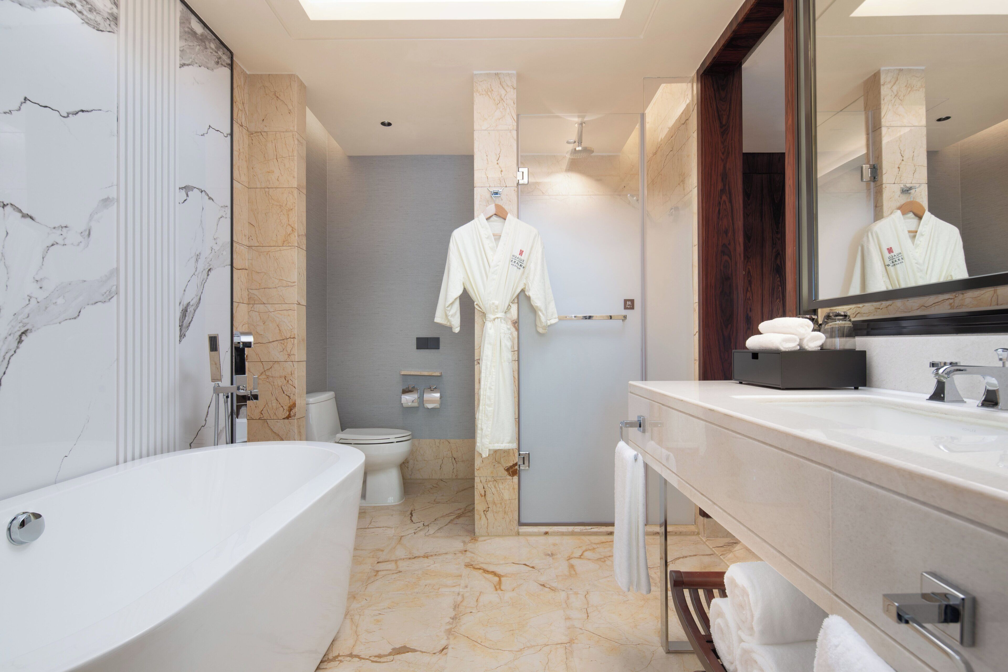 A modern bathroom with a freestanding bathtub, a large mirror, and a towel rack.