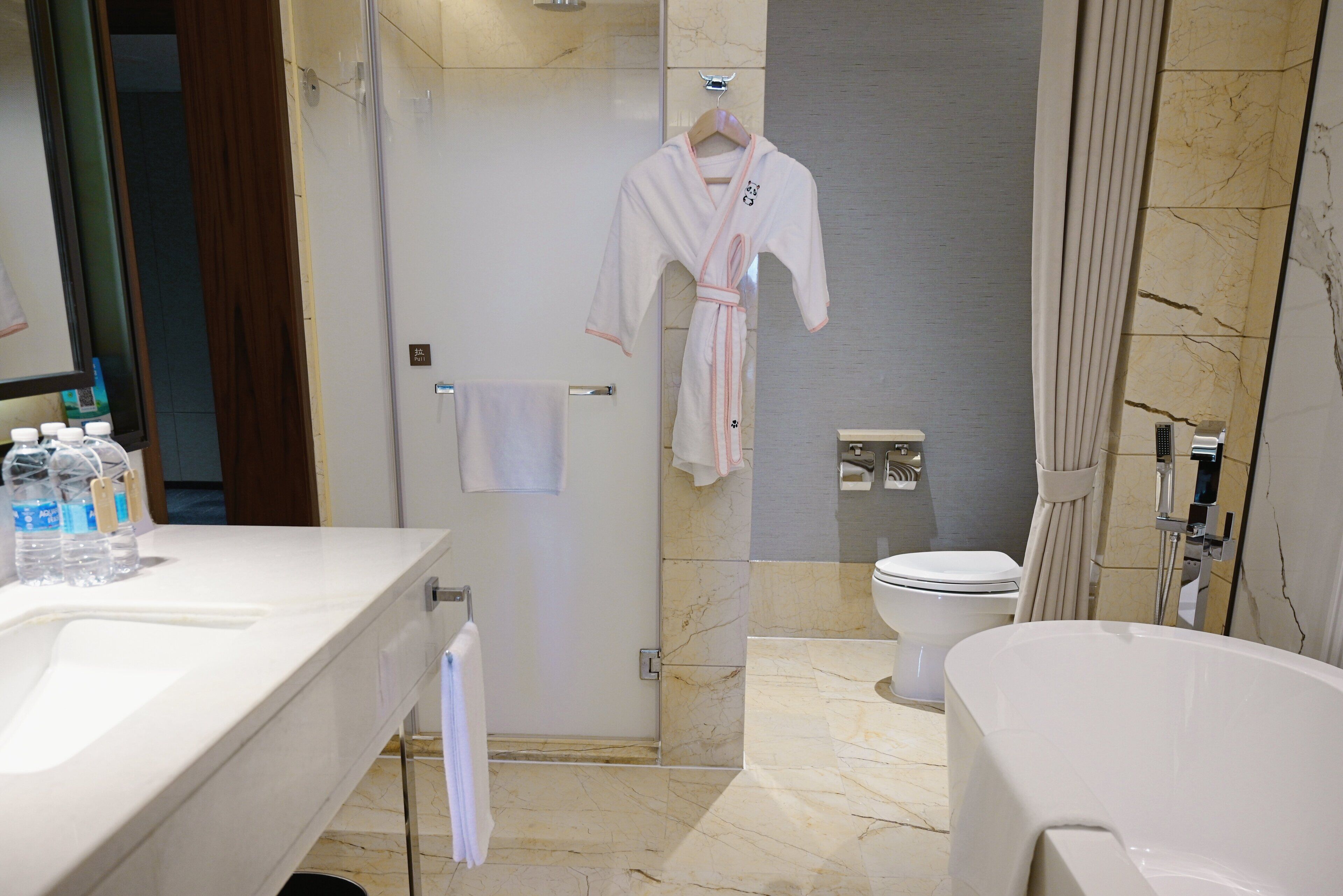 A modern bathroom with a white bathtub, a toilet, and a shower area.
