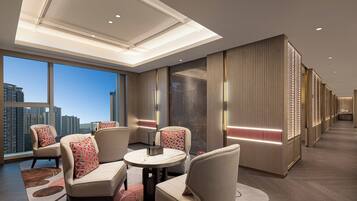 A hotel lobby with a high ceiling, modern furniture, and a view of the cityscape.