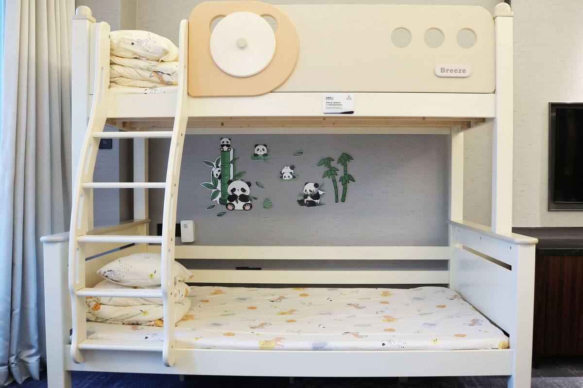 A bunk bed with a panda-themed wall sticker, a 'Breeze' pillow, and a small shelf.