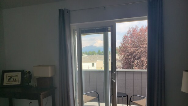 Una habitación con puerta de cristal corredera que da a un balcón exterior con dos sillas.