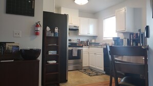 Una cocina compacta con armarios blancos, horno integrado y cafetera.