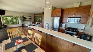 A modern kitchen with wooden cabinets, a stainless steel refrigerator, and a built-in oven. - Points West Oceanfront Resort 1 Bed Ocean Point Suite B (Sooke)