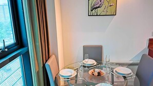 Un comedor con una mesa de vidrio, sillas y un cuadro en la pared.