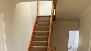 Una escalera de madera con escalones alfombrados que conduce a un dormitorio con cama y mesita de noche.