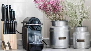 A kitchen counter with a coffee machine, a knife block, and two metal containers with flowers. - Beautiful 3-Bed Apartment in Porto, Portugal (Porto)