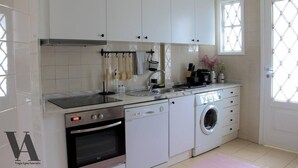 A modern kitchen with white cabinets, a built-in oven, a dishwasher, and a washing machine. - Beautiful 3-Bed Apartment in Porto, Portugal (Porto)