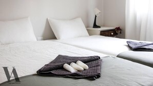 A hotel room with two beds, a nightstand with a lamp, and a folded towel with toiletries on the bed. - Beautiful 3-Bed Apartment in Porto, Portugal (Porto)